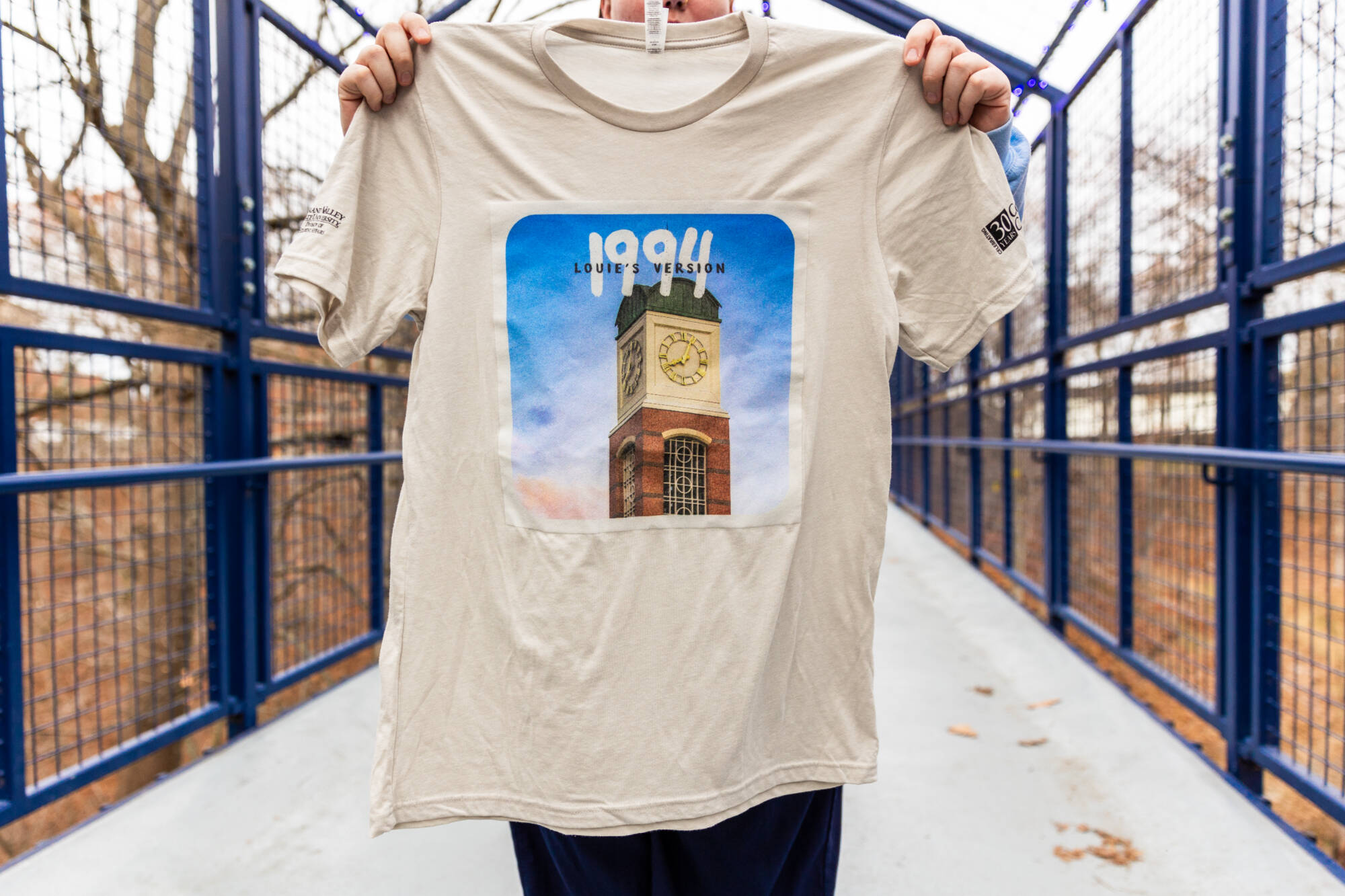 A student holding up a t-shirt featuring a clock tower design and text that reads "1994"